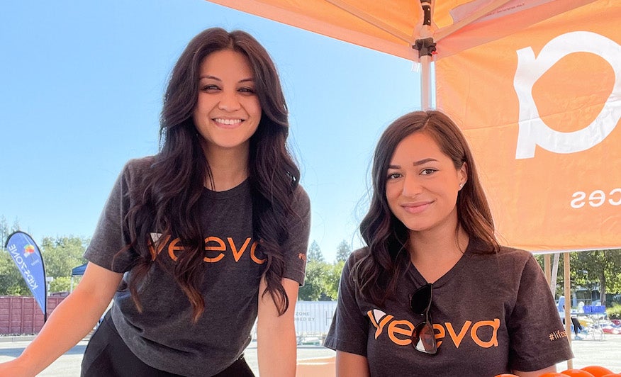 Veeva team members smiling and gathered at Veeva's booth station at a charitable event.