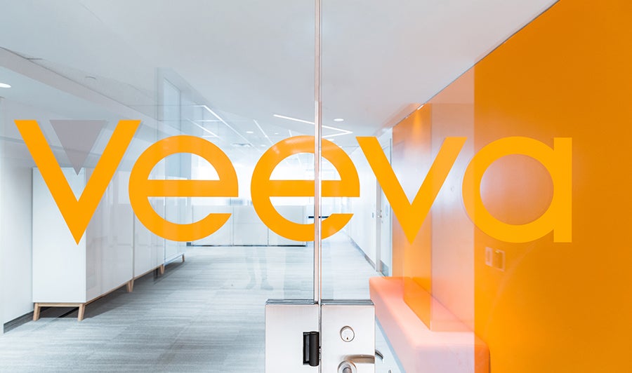 Glass office doors with the Veeva logo across them looking into a clean, bright modern office.